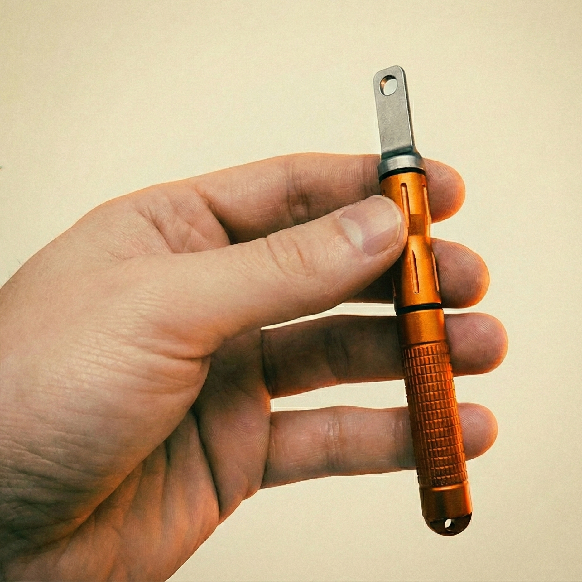 Hand houdt de compacte oranje vuurstarter vast, toont het handzame formaat en de stevige grip